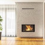 Tall white brick wall with fireplace insert behind well lit room with wood flooring - KreteworX fireplace Idaho Falls ID